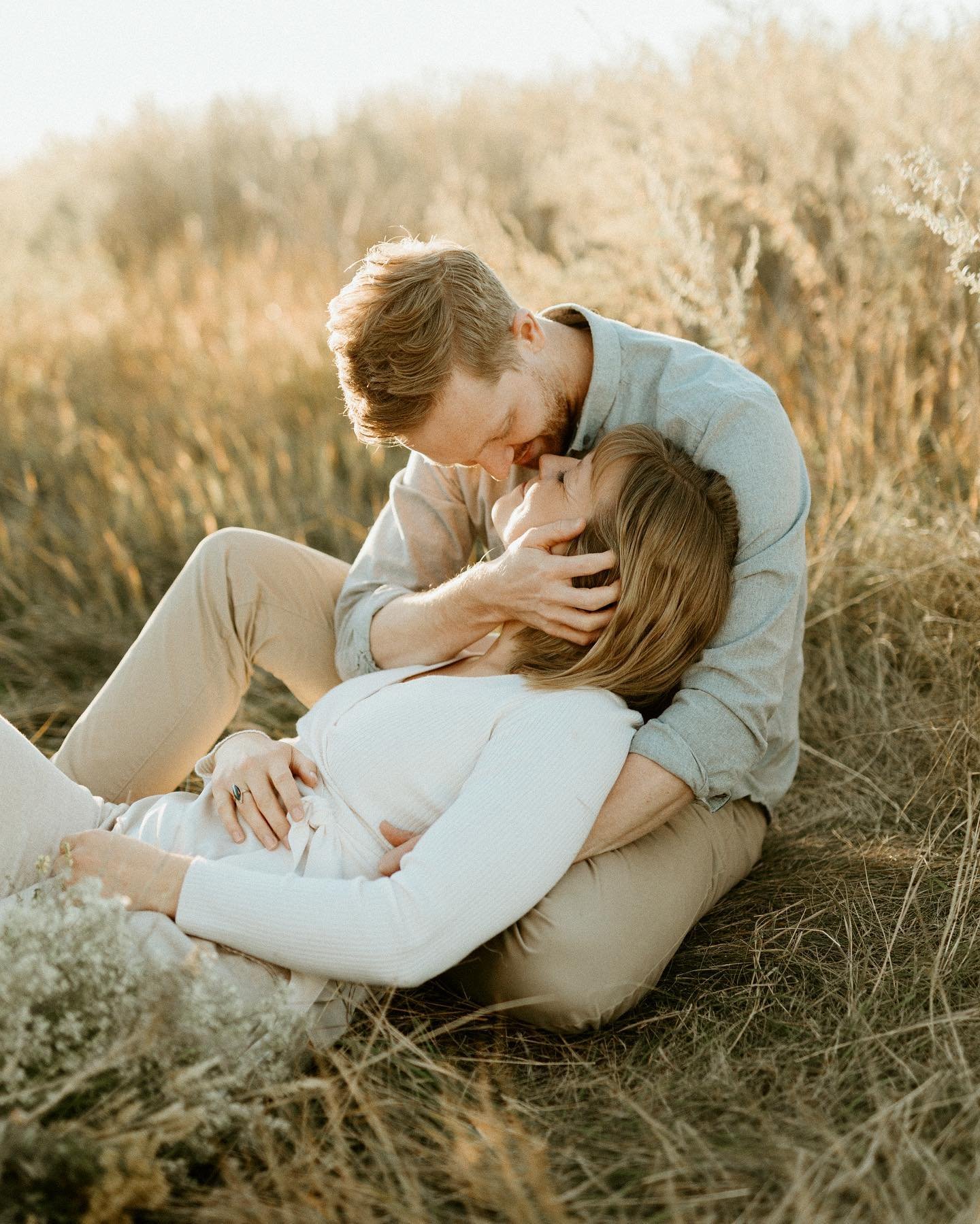 Woman in white shirt laying kissing man in the grass